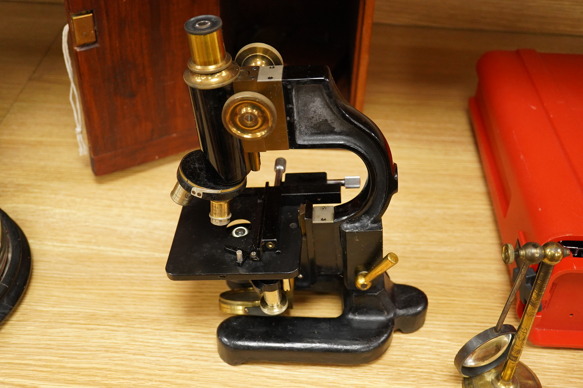 An early 20th century pine and plywood cased microscope by C.Baker, London, containing an integral drawer with alternative lenses, and a magnifying glass on a brass stand, the case dimensions; 38cm high, 18cm wide, 27.5c